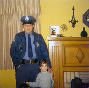 Dad in his police uniform posing with Tommy by the fireplace